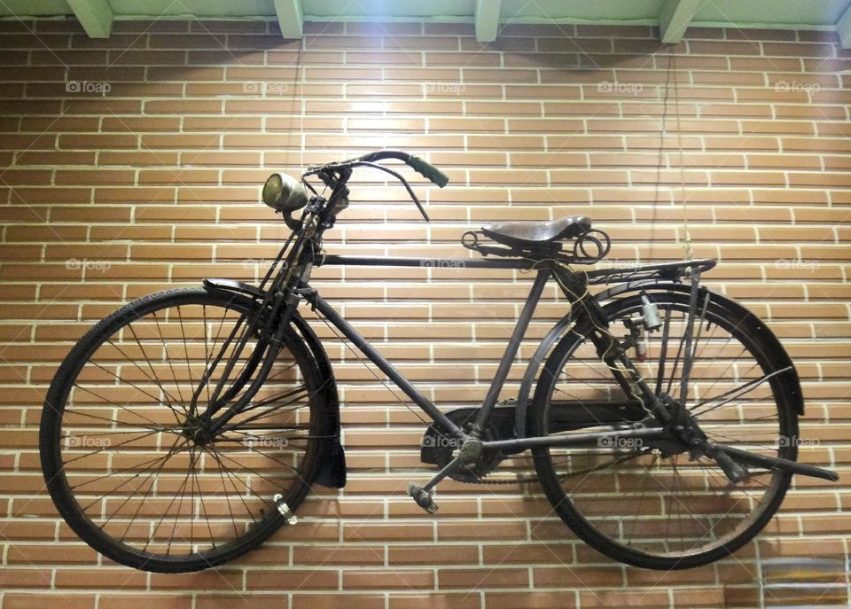 black bicycle hanging on red brick wall