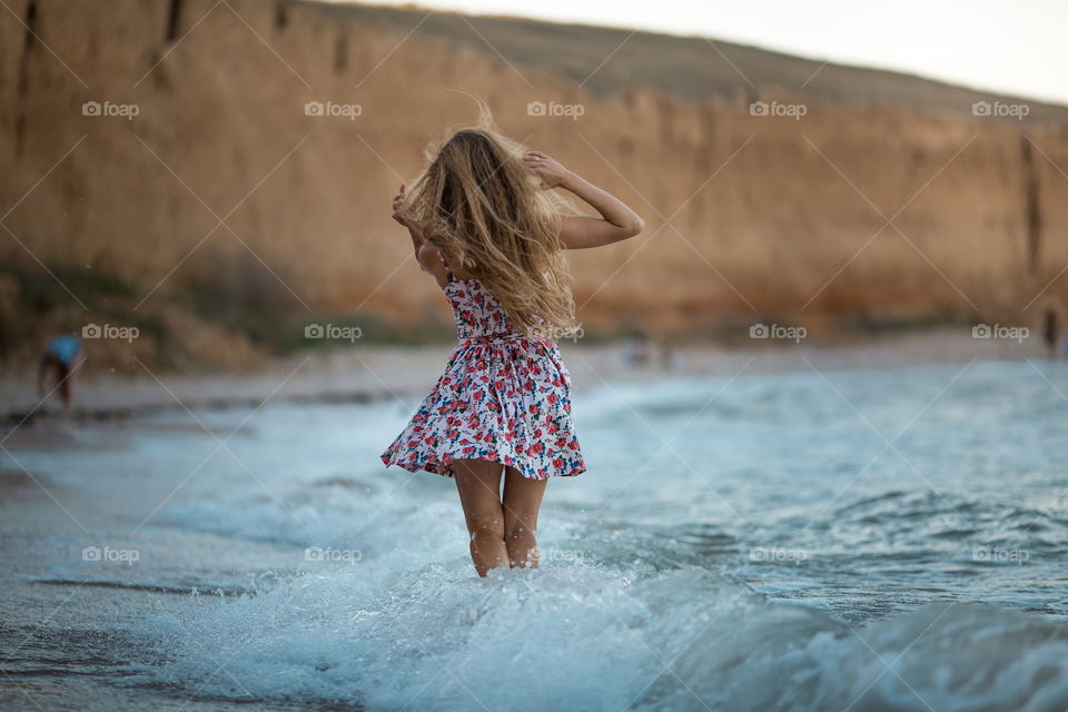 Portrait of beautiful young woman near the sea at sunset