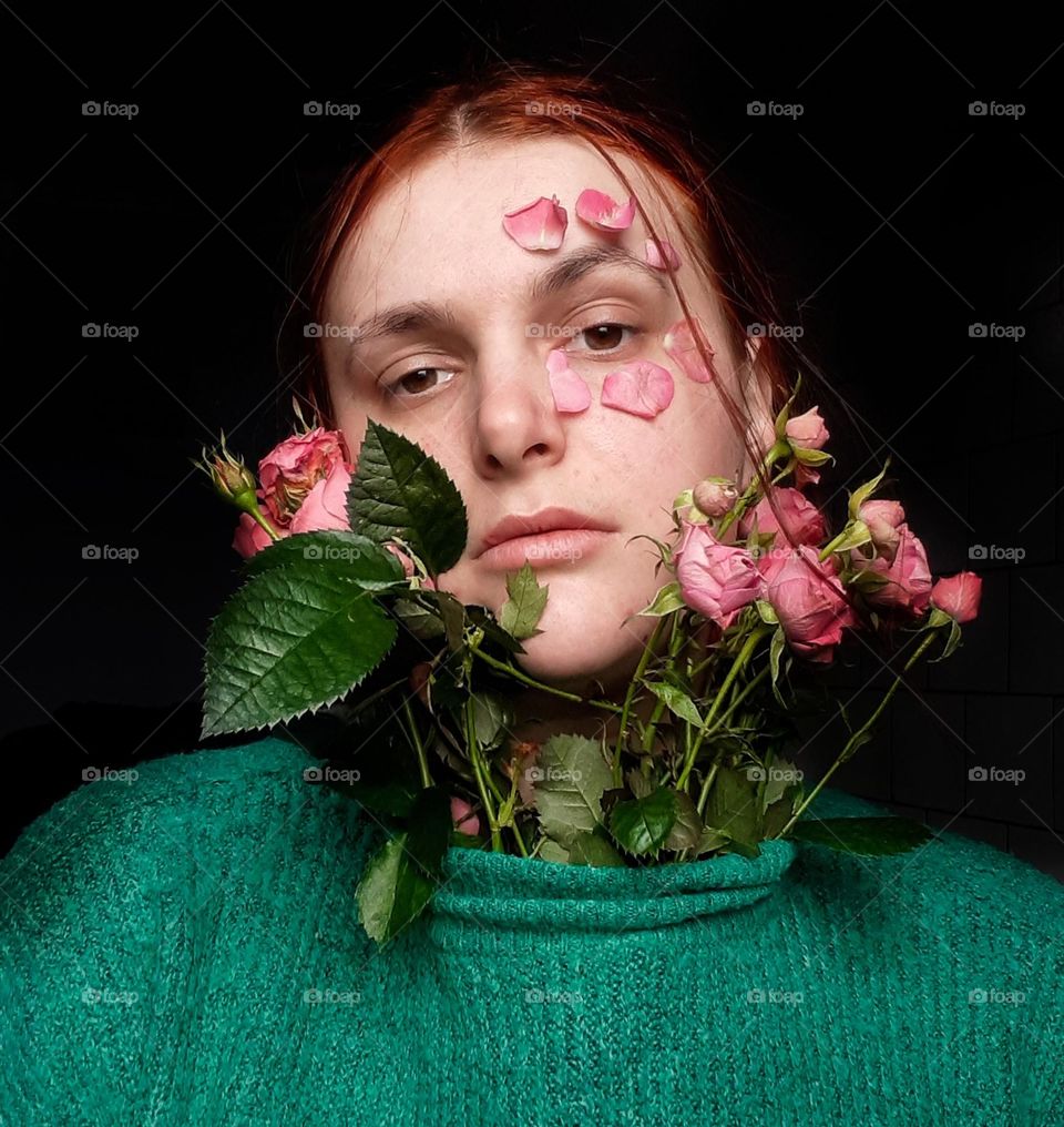 original, floral, female portrait with pink roses and rose petals near the face and in a split sweater