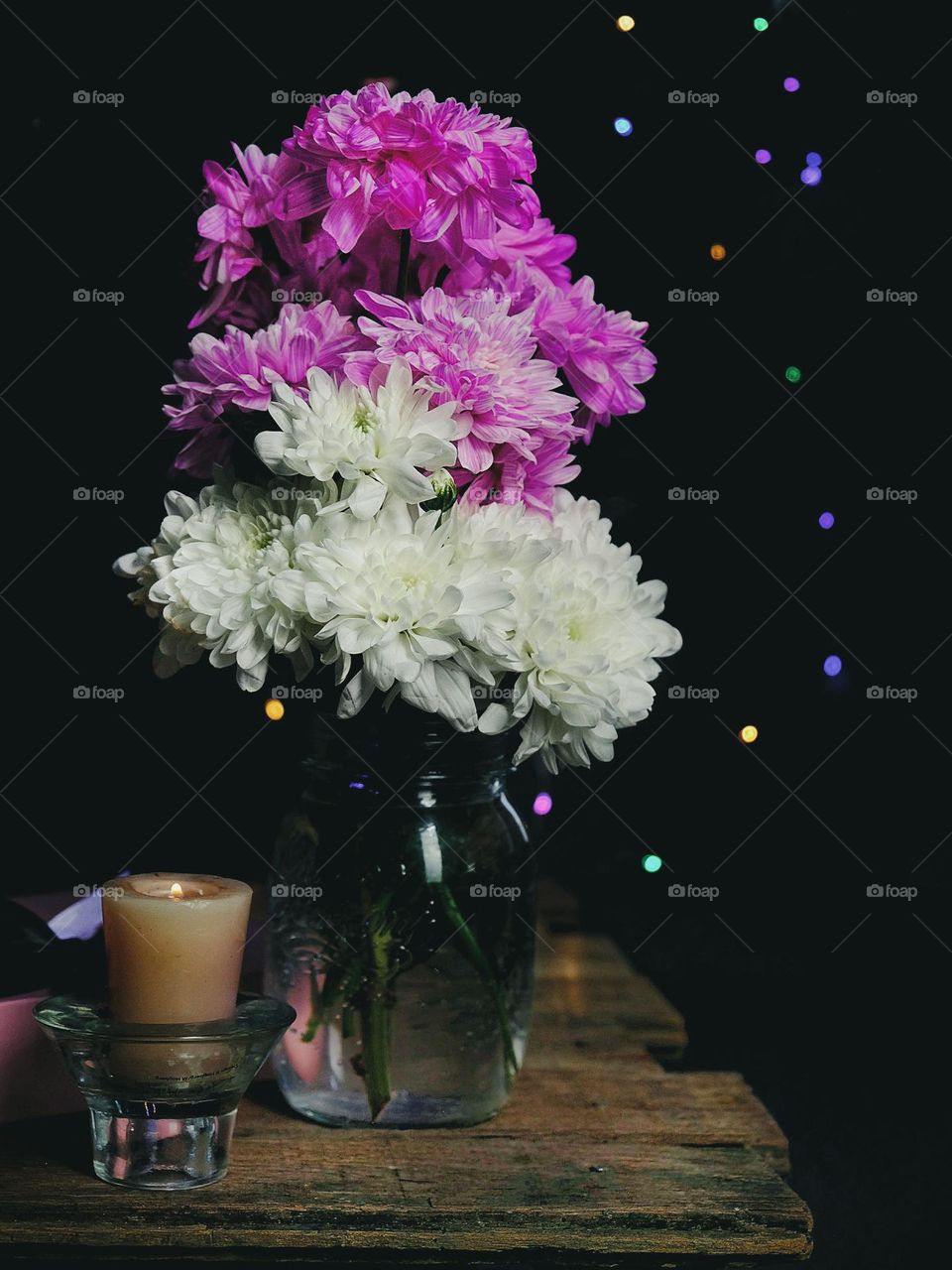 Fresh flowers in the vase on the wooden table with a dark background.