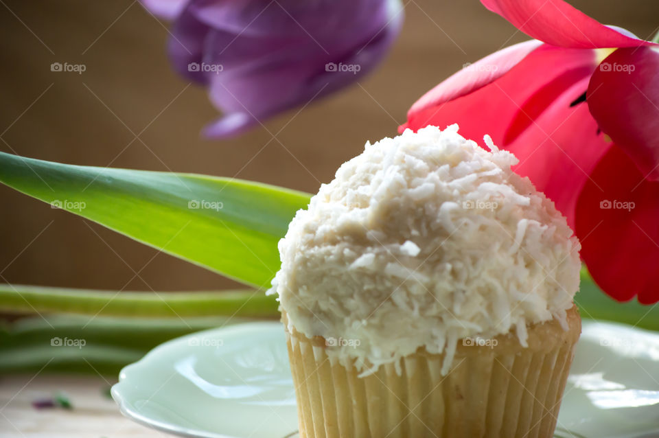 Coconut cupcake on table in plate with beautiful flowers 