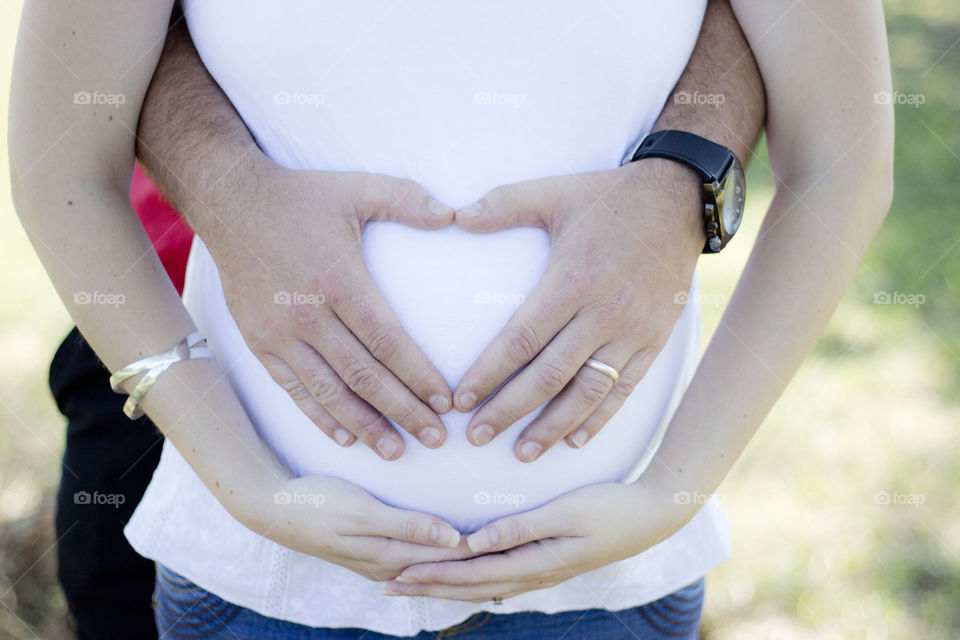 hands creating a heart shape on her tummy showing real love