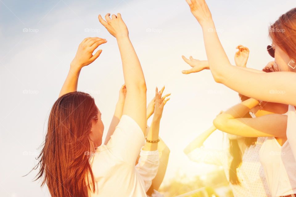 Group of young happy dancing tan girls on blue sky background, summer time, open air party