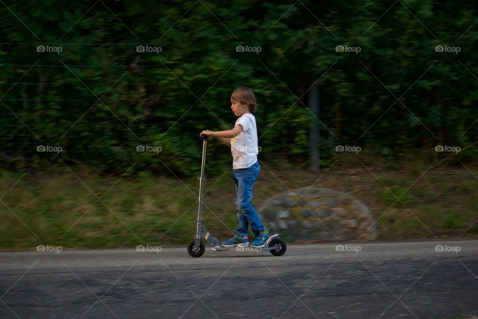 Young Boy Riding A Scooter 