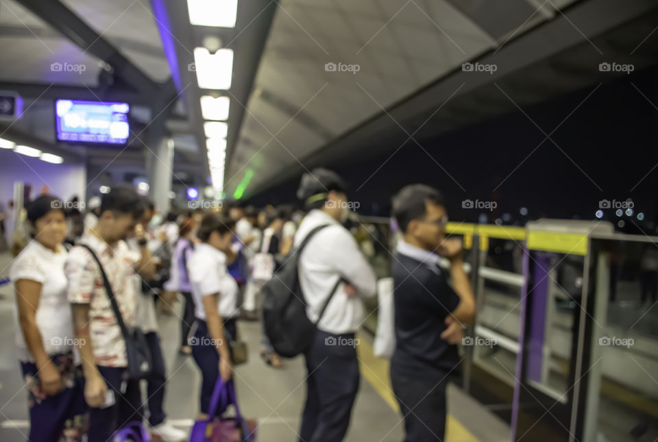 Blurry image of passengers stand waiting for the train.