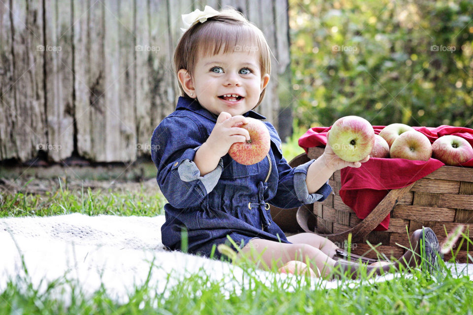 Red apples in brown basket with little girl