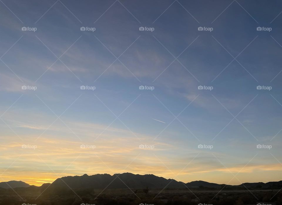 A yellow sunset with mountains and clouds. 