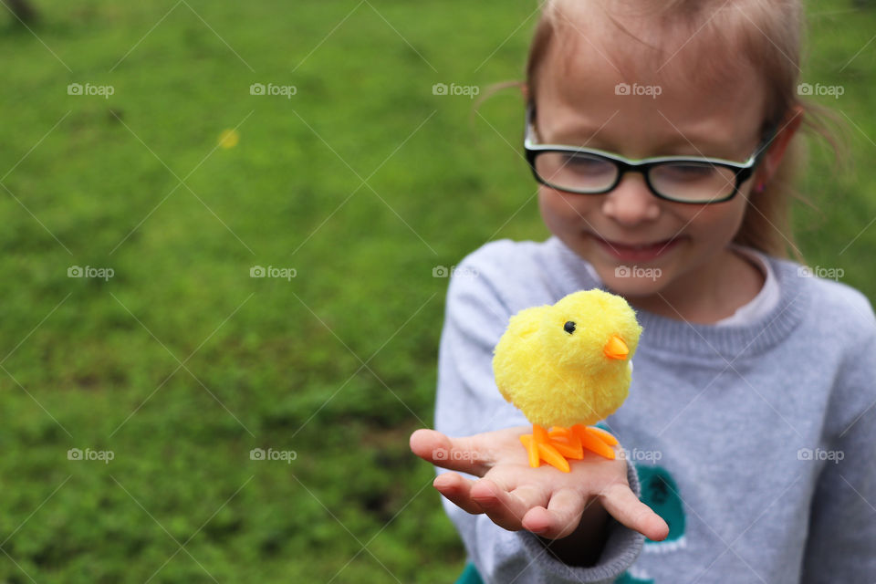 Child holding a toy chick in her hand