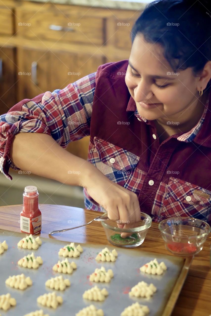 Woman smiles while making cookies, moments of joy wile baking, moments of happiness in the kitchen, woman enjoys baking homemade cookies for the holidays 