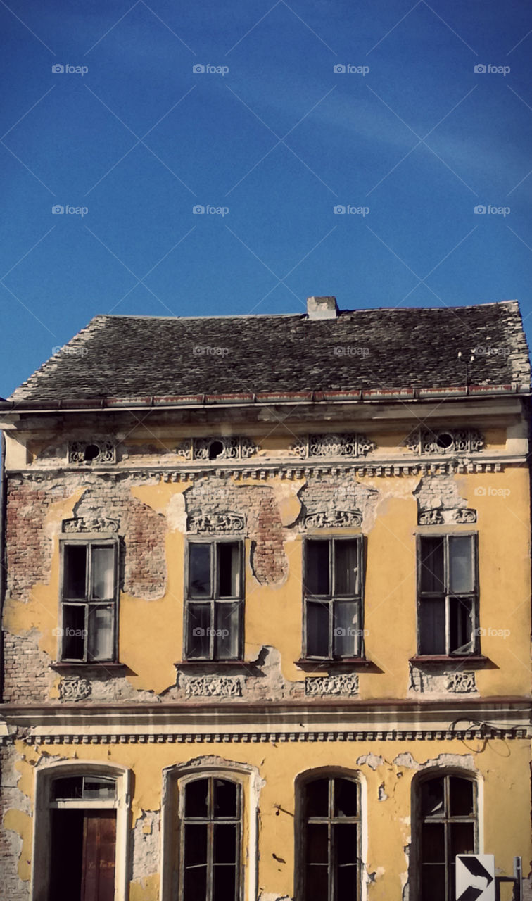 a very old yellow house and blue sky. ruin, retro