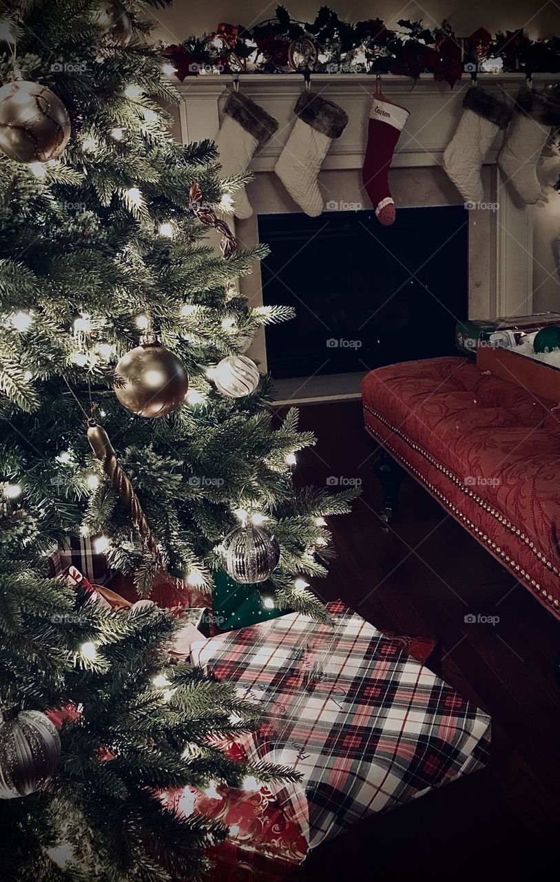 Christmas tree gleaming in the night while stocking is hung by the fireplace 