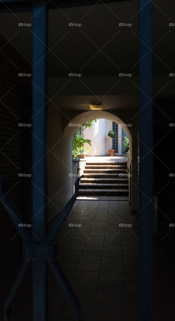 dark entrance through bars with steps and house door in background
