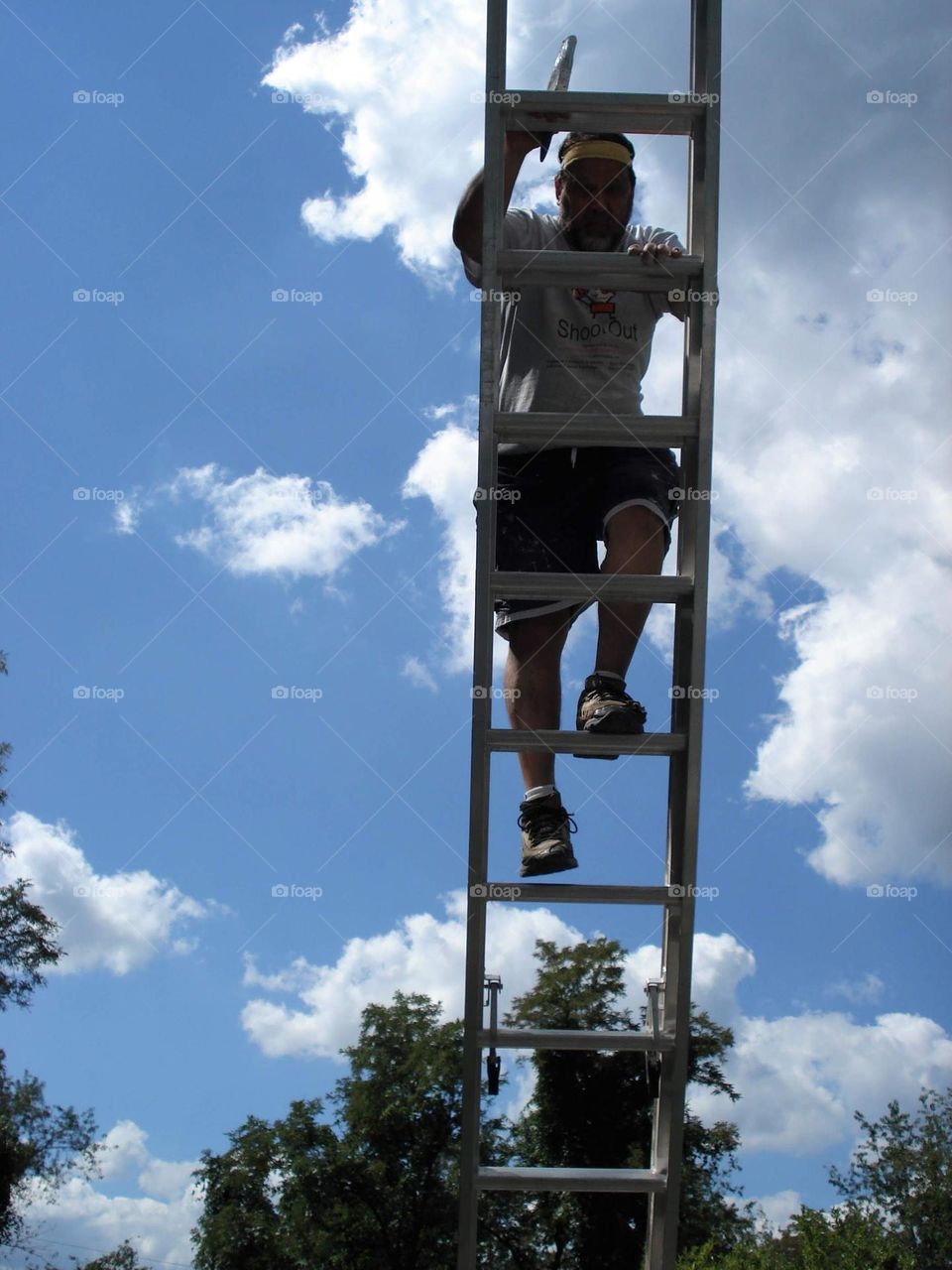 Man climbing a ladder to paint a house