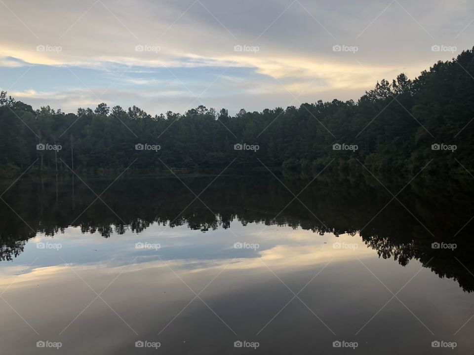 Beautiful lake with trees and sky reflected o. The smooth as glass water.