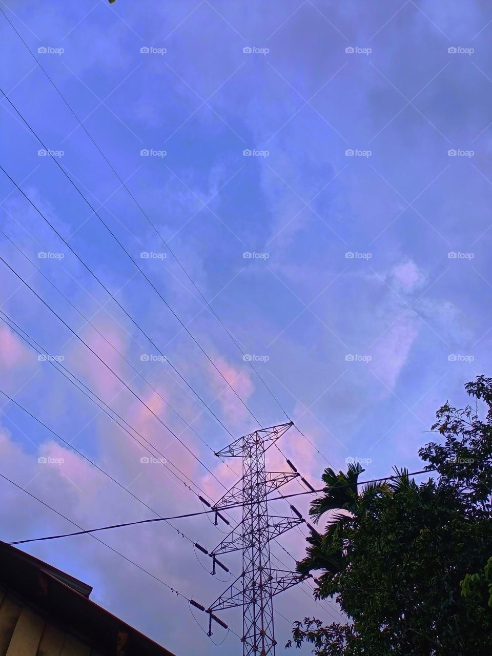 High voltage transmission towers with blue sky background at afternoon.