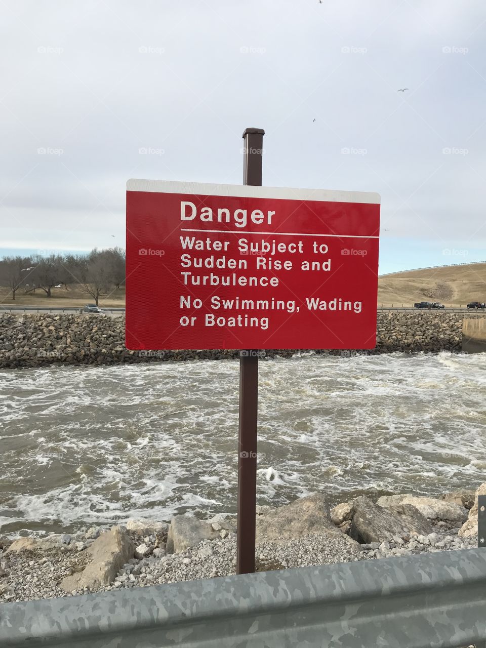 US Army Corps of Engineers, Lake Oologah water release channel during water release in winter, January, sign warning of Danger, riprap along water in channel to prevent erosion.