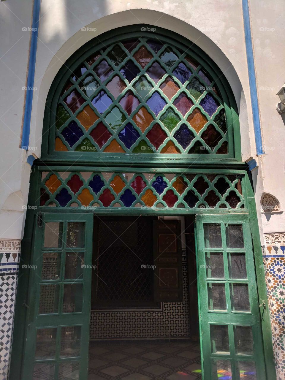 Ornate Green Door with Colorful Diamond Pattern Stained Glass and Ceramic Tile Mosaic Walls in the Bahia Palace in Marrakech in Morocco