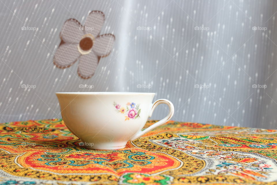 porcelain tea cup on traditional coloured textile material