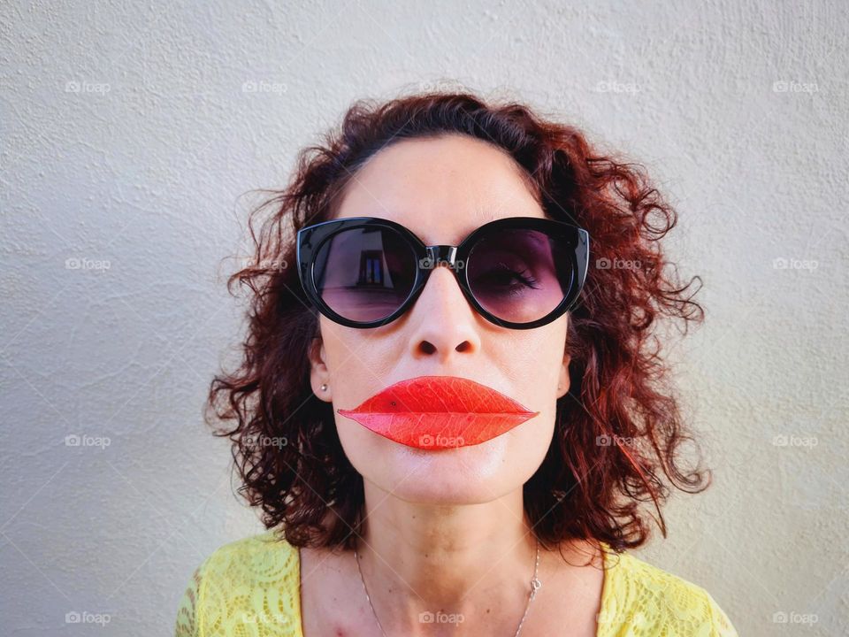 woman has a red leaf on her lips