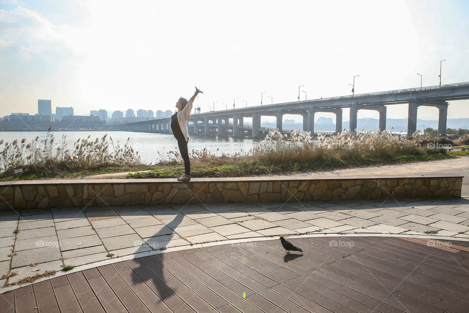 Girl streching, han river and bridge in Seoul in the background. 