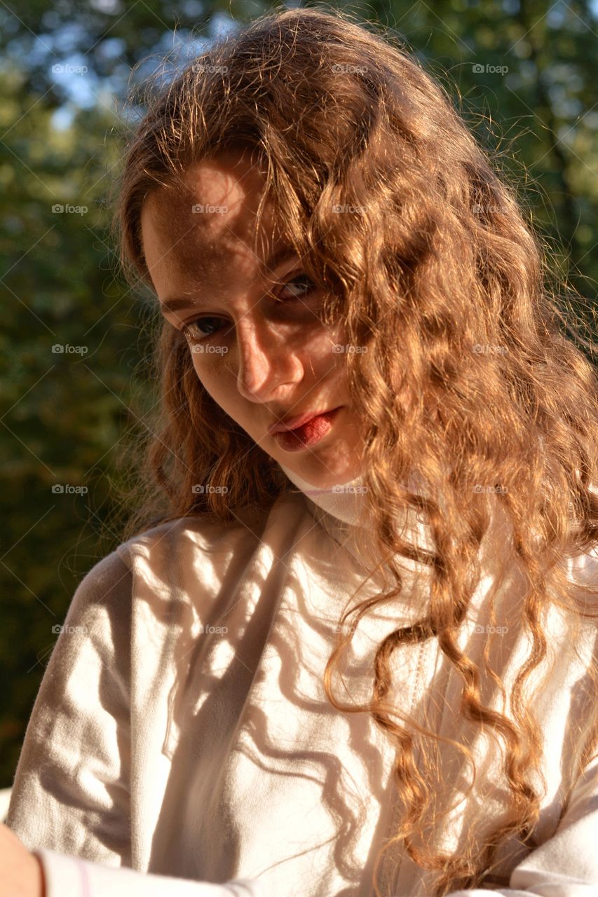 girl portrait in sunlight and shadows outdoor green background summer time