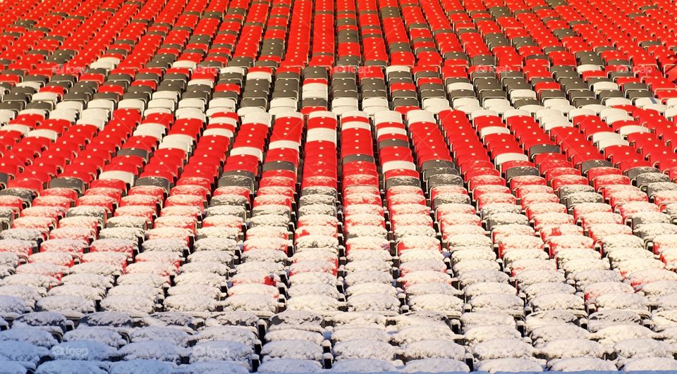 Red, grey and white stadium seats covered in snow.