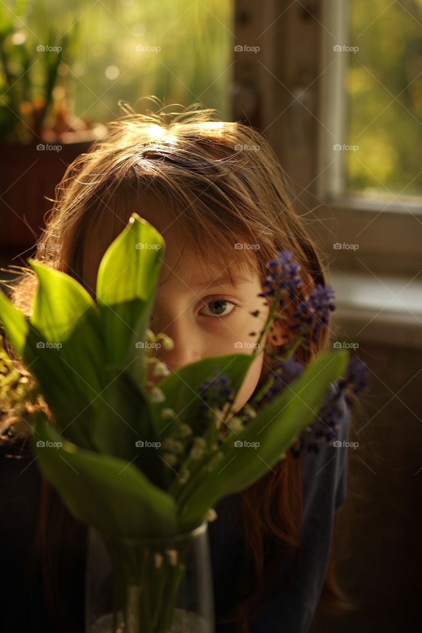 Portrait of a cute little girl in spring lilies of the valley