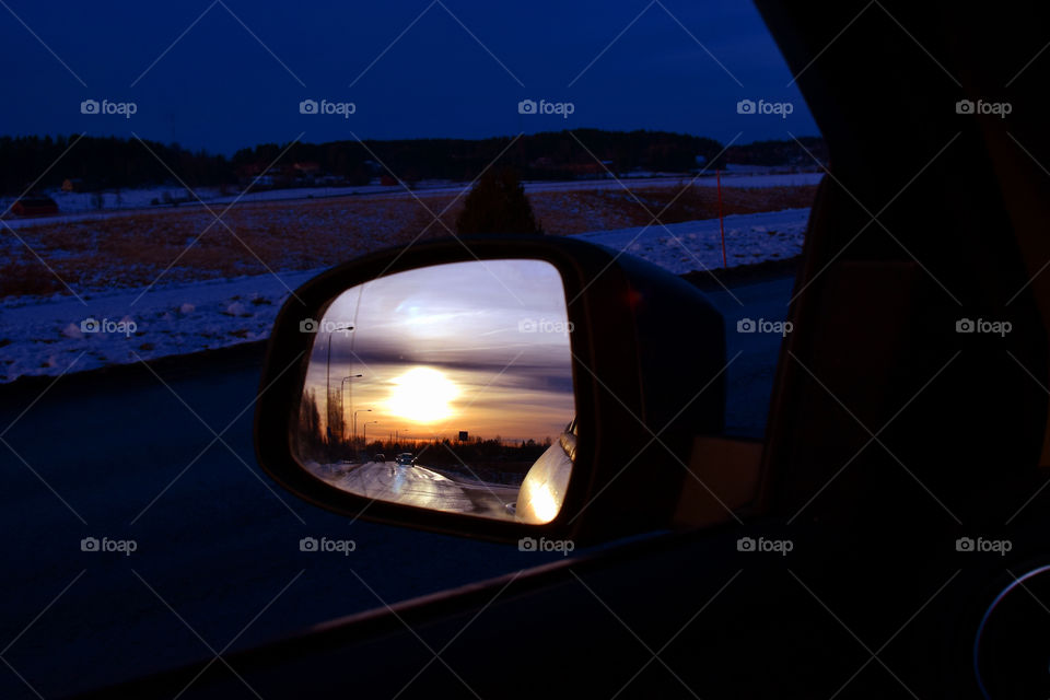 Sunset reflected in car side-view mirror.