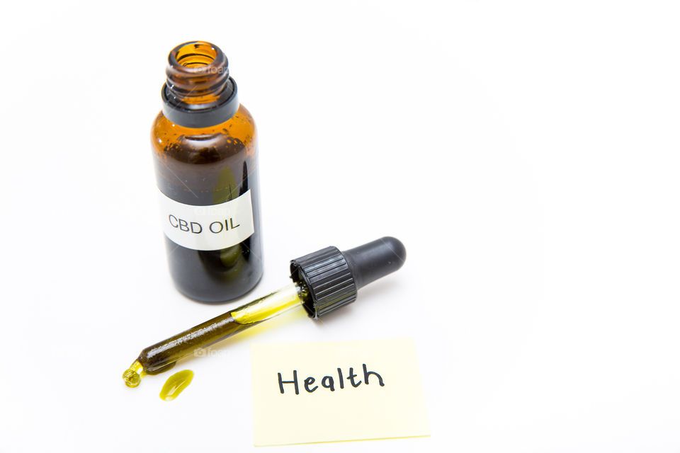 Product cbd oil bottle with dropper and oil on pure white background. Health written on note.