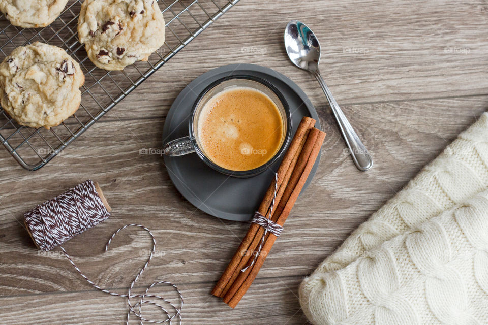 Cup of hot espresso styled with fresh spices, cookies and a warm blanket