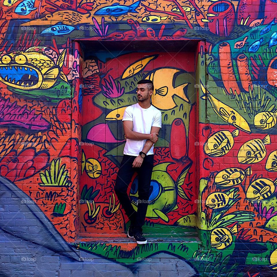 Young man standing in front of graffiti wall