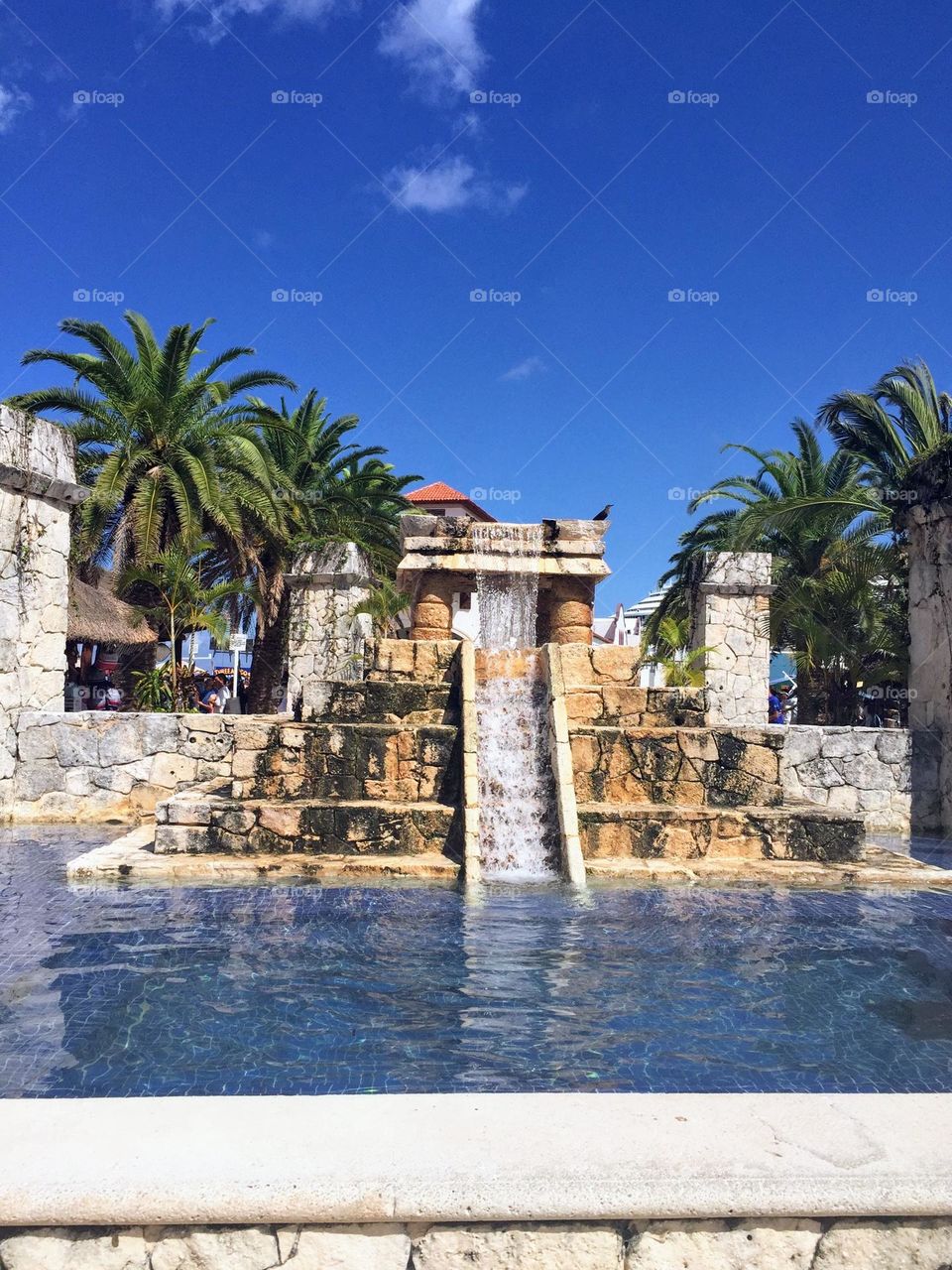 Unique old maya pyramid shaped fountain with palm trees around 