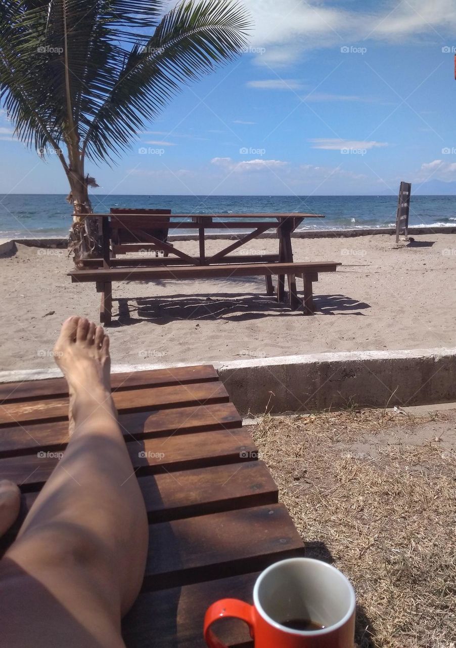 Looking at the sea with a cup of coffee in a sunny day