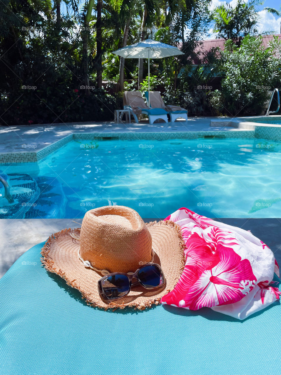 Sunglasses and hat by pool