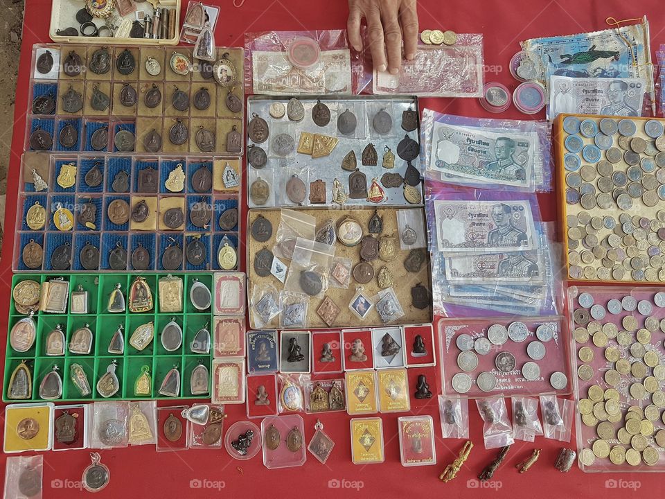 stall of antique buddhist amulet, coins and bank note, money in Thai currency at a flea market