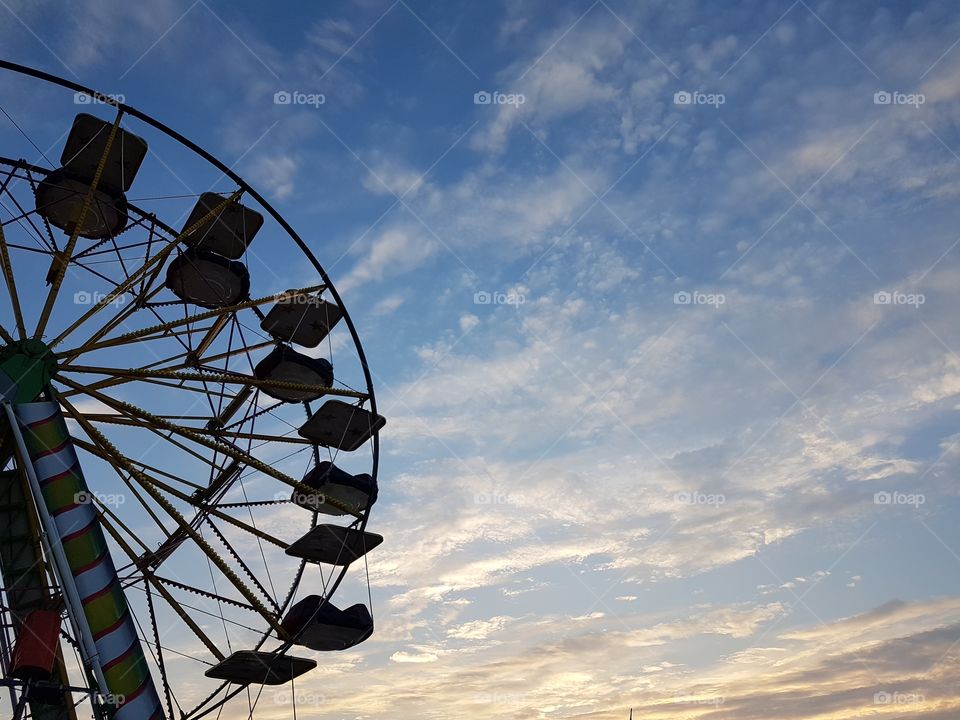Silhouette of ferris wheel at sunset with clouds