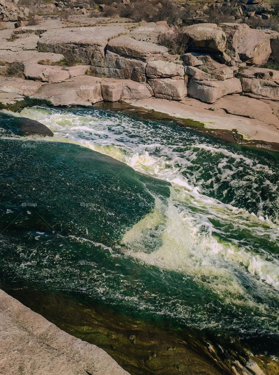 Blue green water in the waterfall between granite rocks