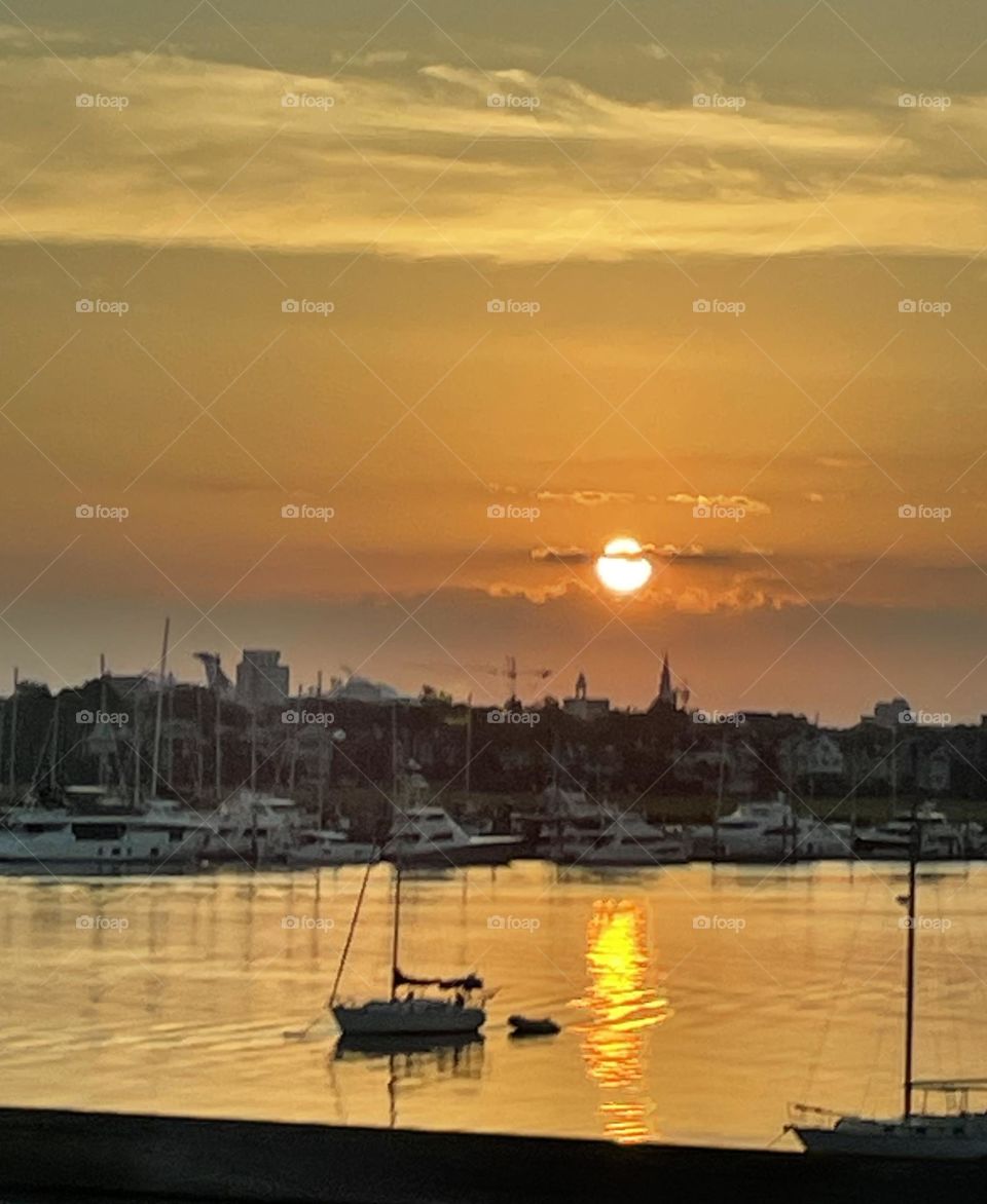 Majestic sunrise in the harbor. Peaceful sky and water with the suns reflection. 