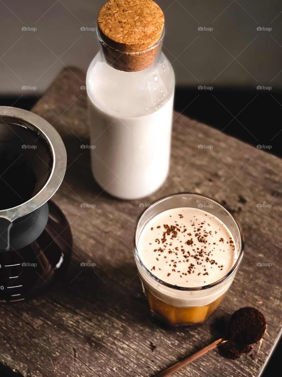 Close up view of caffe latte foam texture in a cup, a bottle of milk and coffee dripper at the side
