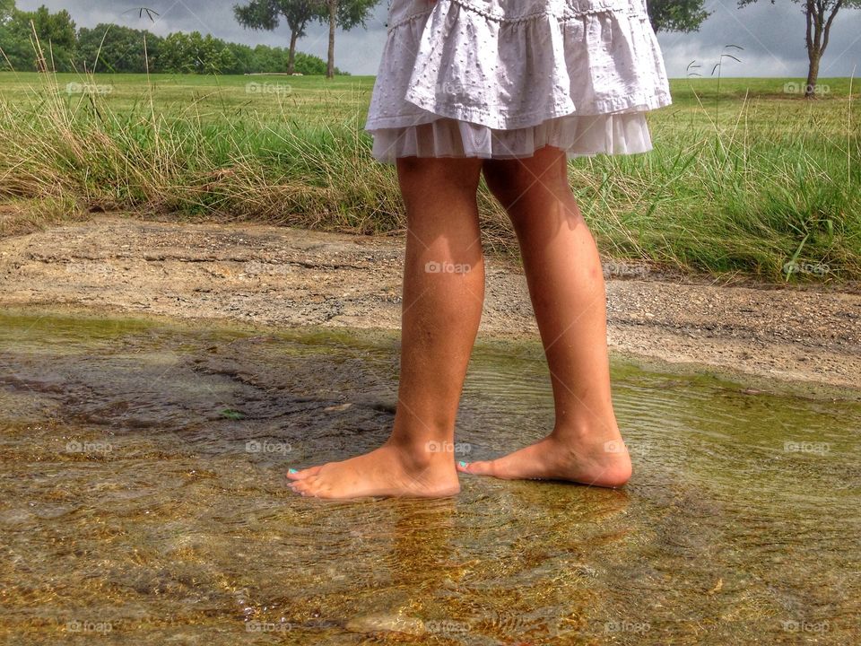 A day in the life. Girl walking through a small stream of water