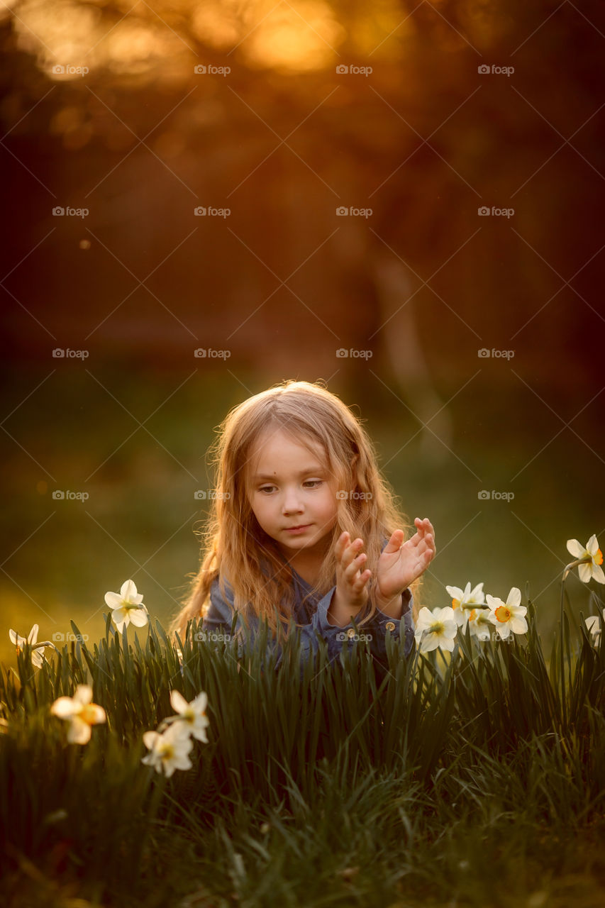 Little girl with narcissus at sunset