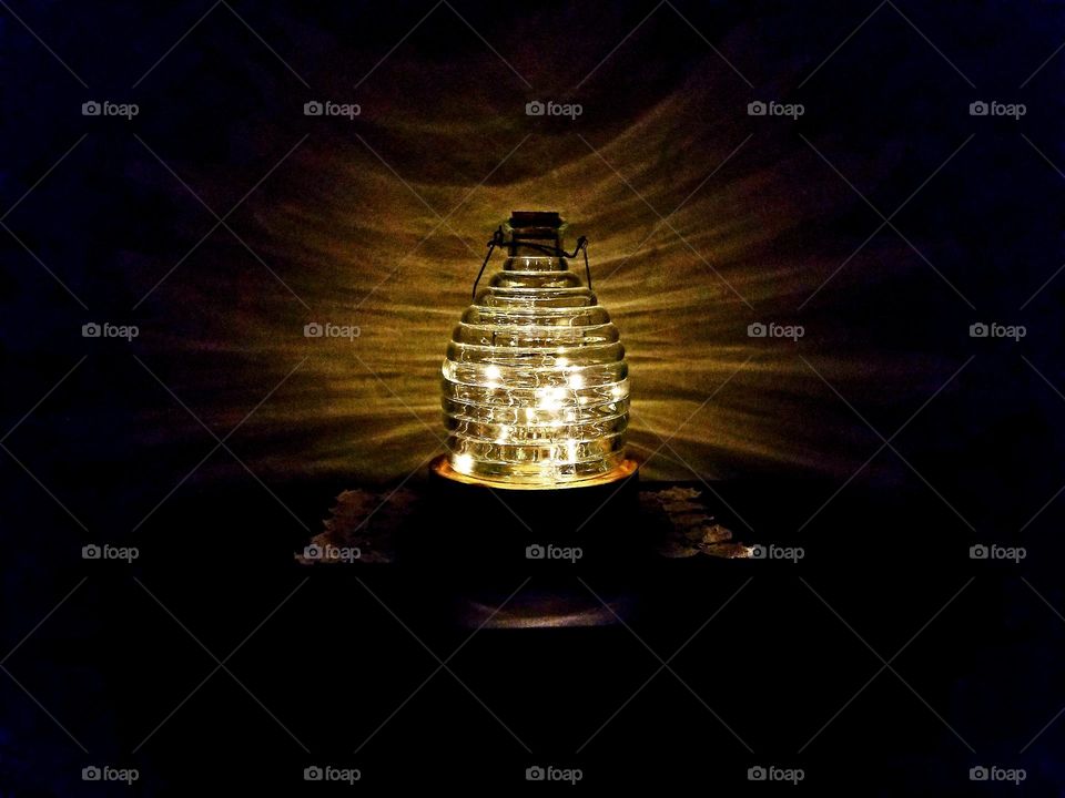 Honey Jar with small LED string lights made into a lamp reflecting off the wall at night