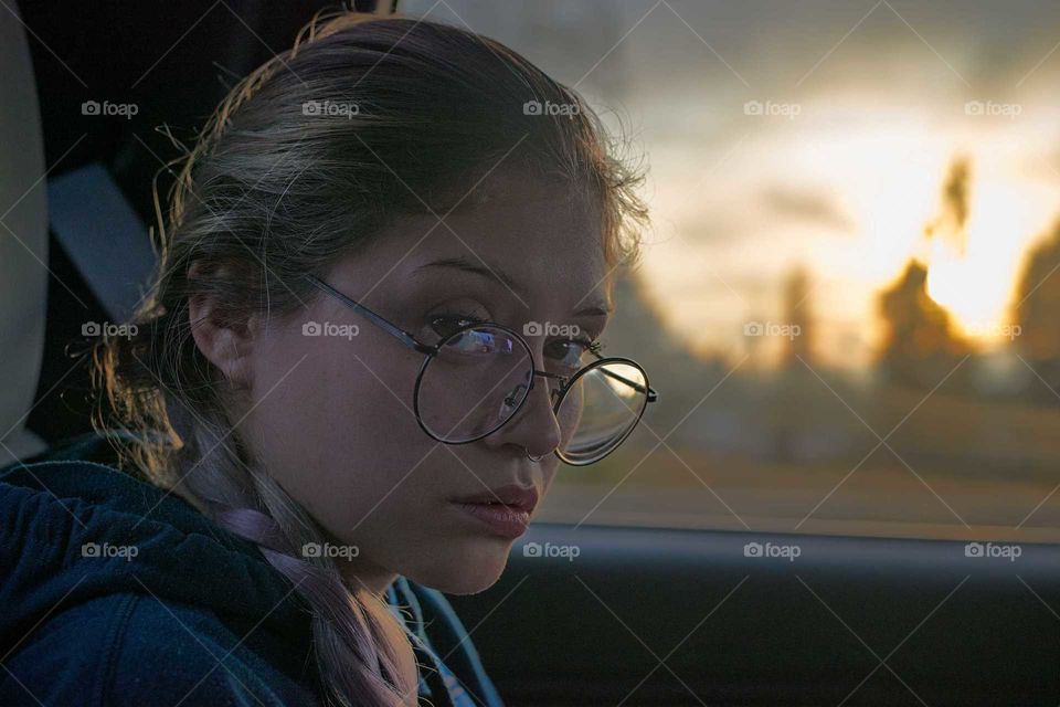 young woman with braided hair glasses, in the backseat of the vehicle