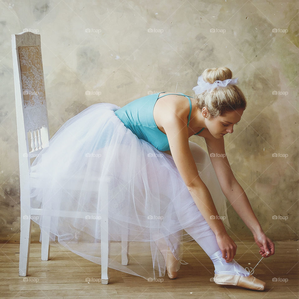 Young and graceful ballerina in pointe shoes and a tutu dances in a studio. Choreography and dancing classes concept. Creative ideas of ballet posing and performance.