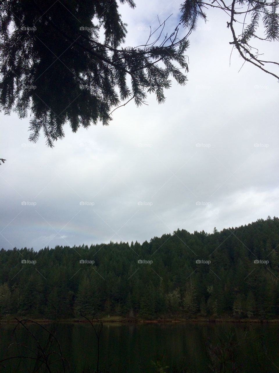 Cloudy day at the lake With a little rainbow peeking through 