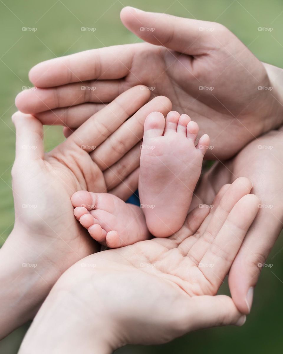 Hands wrapped around baby foot.