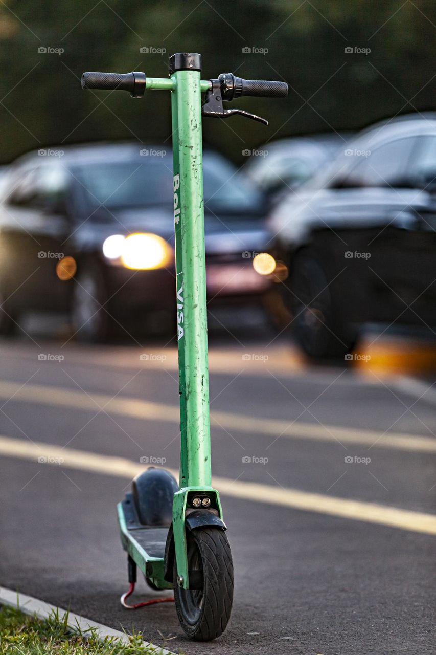 Eco friendly urban gadget. Electric scooter on the background of evening traffic.