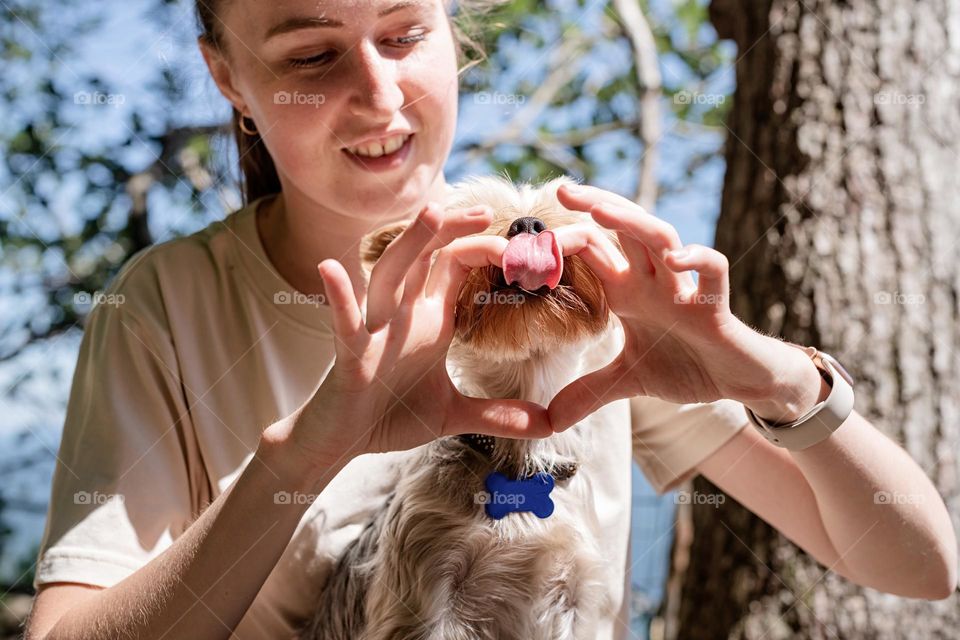 woman making heart gesture to her dog