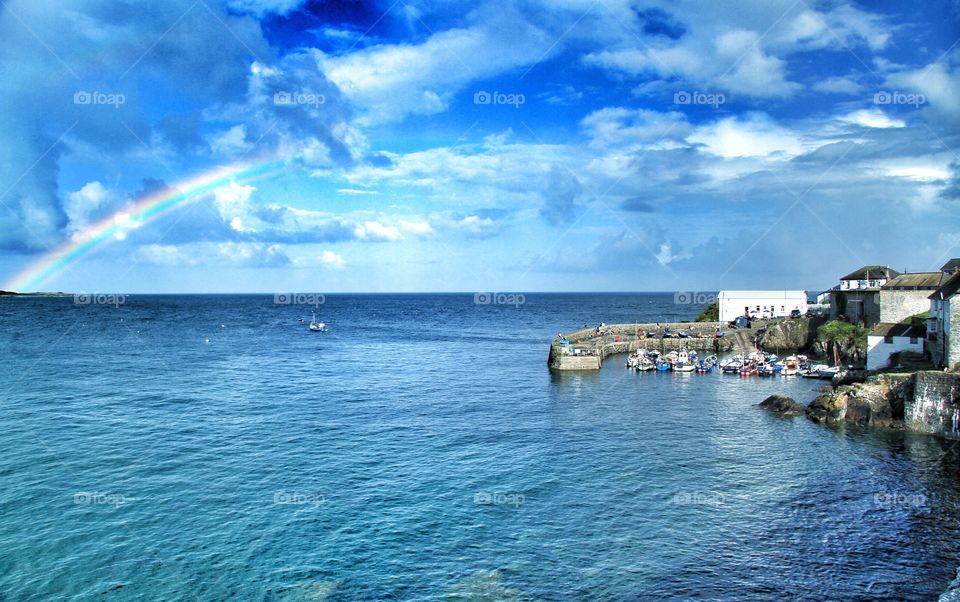 Rainbow Village. A Coastal scene of a rainbow stretching over a bay next to a Cornish fishing village.