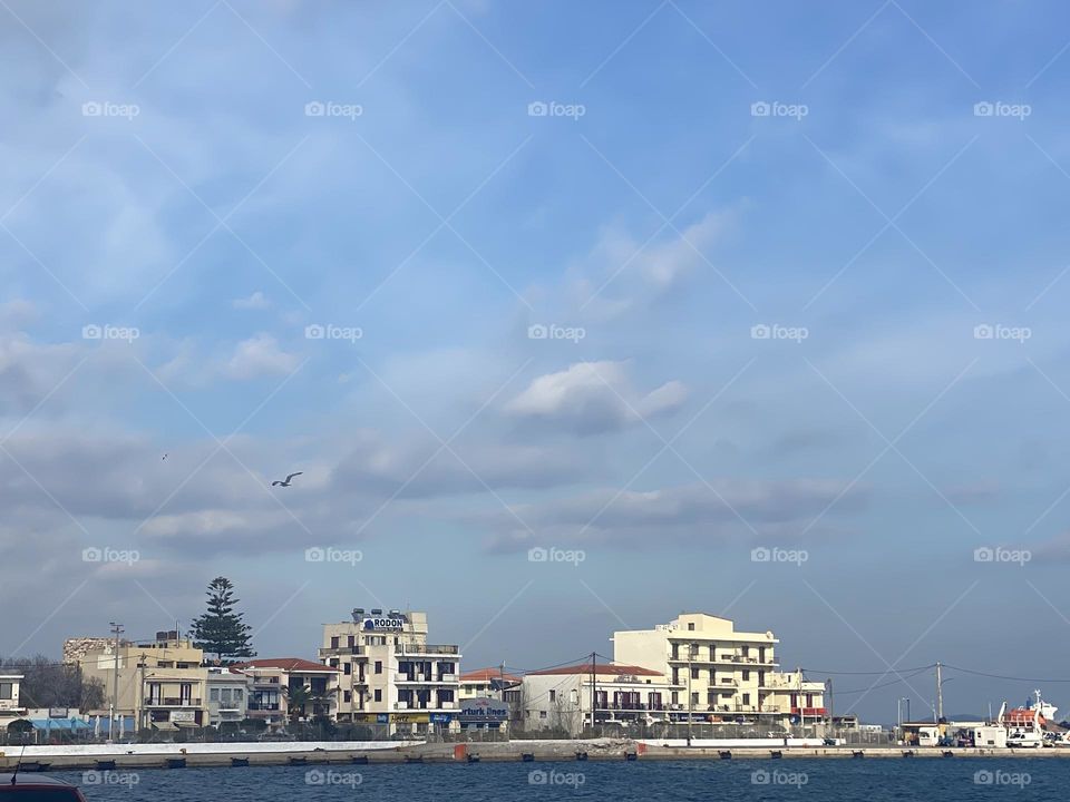Winter in Greece Island.Sea,buildings ,cloudy sky and the bird flying made this beautiful photo.❤️